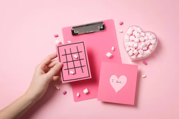 Hand holding pink card with heart calculating their love compatibility score